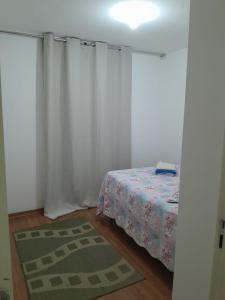 a bedroom with a bed with white curtains and a rug at Lar feliz in Juiz de Fora