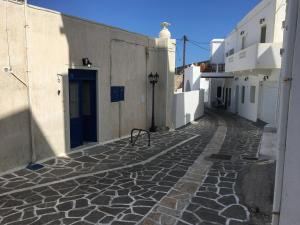 a cobblestone alley with a blue door and white buildings at MilosBluePearl in Triovasálos