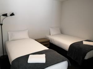 a room with two beds and a lamp at Residence du Parc - Luxury Apartment in Queenstown