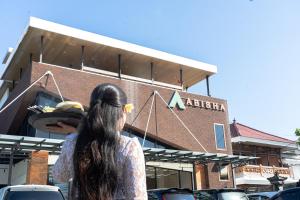 Eine Frau steht vor einem Gebäude in der Unterkunft ABISHA Hotel Sanur in Sanur