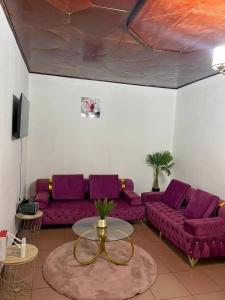 un salon avec des canapés violets et une table dans l'établissement Sacha appartement 2 chambres, à Yaoundé