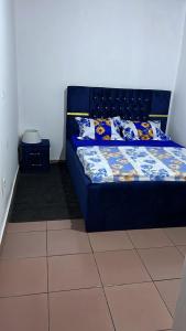un lit bleu dans une chambre avec un sol carrelé dans l'établissement Sacha appartement 2 chambres, à Yaoundé