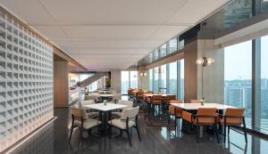a restaurant with tables and chairs and large windows at Jinmao Grandee Hotel Ningbo in Fenghua