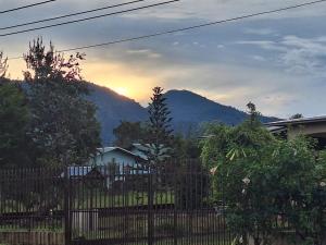 a fence in front of a house with a mountain at Cabaña en Volcan in Volcán