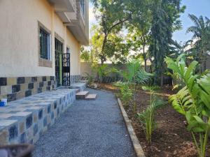 a walkway leading to a building with plants and trees at Stay with Adhiambo - FigTree Apt- Studio in Kilifi