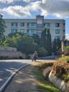 a person riding a motorcycle down a road in front of a building at Stay with Adhiambo - FigTree Apt- Studio in Kilifi +2 photos