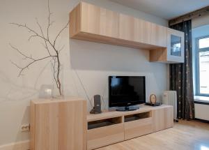 a living room with a tv on a wooden entertainment center at PiterStay Nevsky 32 in Saint Petersburg