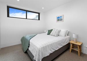 a white bedroom with a bed and a window at Views at 59 in Gerroa