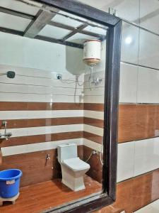 a bathroom with a toilet and a mirror at Corbett Sunrise India Homestay! in Rāmnagar