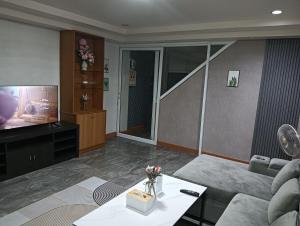 a living room with a couch and a tv at Ben House Hatyai in Hat Yai