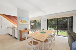 a kitchen and dining room with a wooden table and chairs at Avoca Beach Living in Avoca Beach