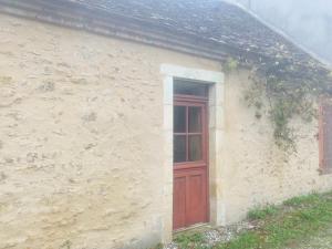 a brick building with a red door and a window at Charmante petite maison pour deux in Badecon-le-Pin