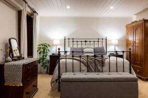 ein Schlafzimmer mit einem Bett, einer Kommode und einem Spiegel in der Unterkunft Seppeltsfield Vineyard Cottage Luxury Romantic Getaway in Seppeltsfield