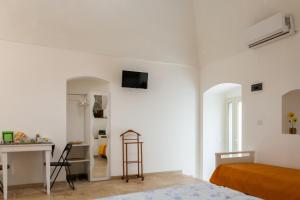 a white bedroom with a bed and a desk and a table at Meridiem in Molfetta