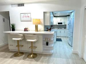 a kitchen with white cabinets and a counter with stools at Amazing beachfront condo at Tides on Hollywood Beach Luxury Resort in Hollywood +32 photos