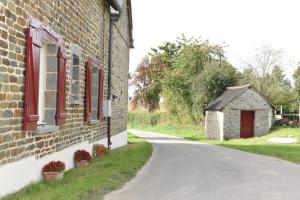 a brick building with red windows and a road at Gîte des champs étoilés in Thuboeuf