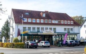 ein großes Gebäude mit davor geparkten Autos in der Unterkunft Hotel Klusenhof in Lippstadt