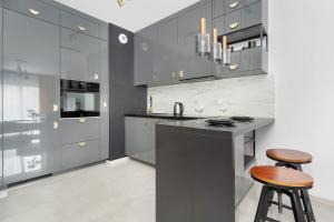 a kitchen with gray cabinets and two bar stools at Lux Traugutta Apartment with Air Conditioning and Parking by Noclegi Renters in Wrocław +13 photos