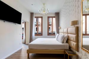 a bedroom with a bed and a flat screen tv at Numa Venice Palazzo Orseolo in Venice