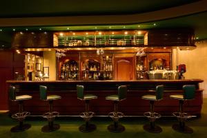 a bar with green bar stools in front of it at Grand Hotel Bucharest in Bucharest