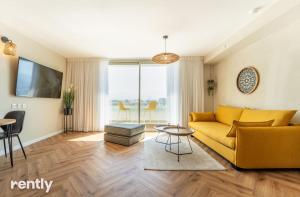 a living room with a yellow couch and a table at Sea side "Sunflower" apartment - by Rently in Eilat