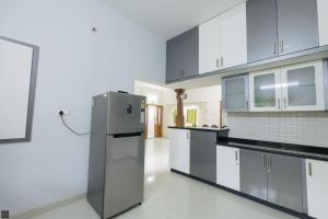 a kitchen with a refrigerator and white cabinets at Reunion Ocean Daaffy - Beach House in Udupi