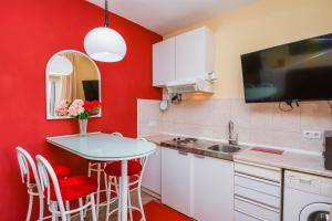 eine Küche mit roten Wänden und einem kleinen Tisch mit roten Stühlen in der Unterkunft Apartments Helios in Kaštela