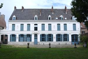 un grand bâtiment blanc avec un toit noir dans l'établissement Château Hôtel de Warenghien, à Douai