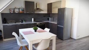 a kitchen with a white table and chairs and a refrigerator at Apartmán Marty in Nové Zámky