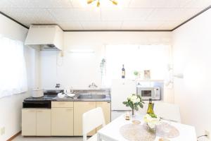 SuizawaにあるSuzuka Smile Roomの白いキャビネットと花のテーブル付きのキッチンが備わります。