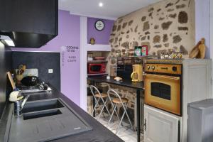 a kitchen with purple walls and a stove and a sink at Maison Irène, Charme et nature pour 2 pers in Véranne +10 photos