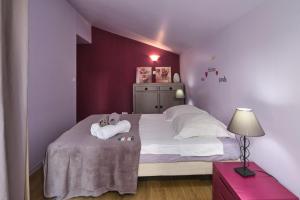 a bedroom with purple walls and a bed with towels at Maison Irène, Charme et nature pour 2 pers in Véranne