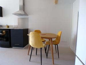 a kitchen with a wooden table and two yellow chairs at L'atypique studio 1 à 3 voyageurs in Bazas