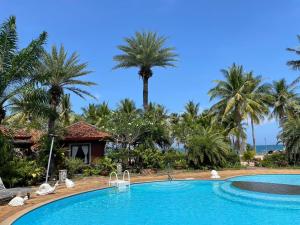 a swimming pool in front of a resort with palm trees at Rachavadee Bankrut Resort in Ban Krut