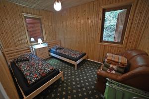 a bedroom with two beds and a leather couch at Casa de vacanta Satic Piatra Craiului La Doi viermi in Satic