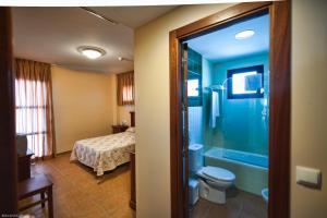 a bathroom with a shower and a toilet and a bed at Hotel Restaurante Campiña Del Rey in Villanueva del Rey