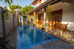 a swimming pool with a wooden bench next to a house at Zichron Rest in Galle