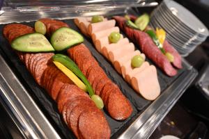 a tray of meats and vegetables with cucumbers and cheese at Fashion City Hotel Superior in Budapest +51 photos