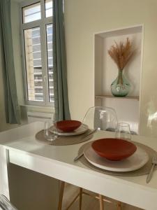 a table with two plates and glasses and a window at Hypnos-Hébergement champenois-Hypercentre in Chalons en Champagne +3 photos