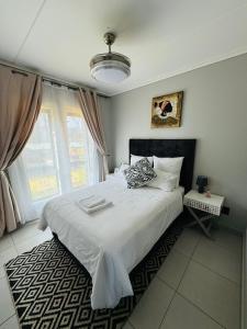 a bedroom with a white bed and a window at Lakhe Lethu Apartment: Green Valley Estate in Nelspruit