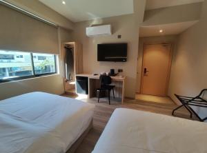 a bedroom with a bed and a desk with a television at Nuvo Hotel in Bandar Seri Begawan