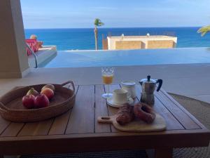 a table with a breakfast of fruit and coffee on a balcony at Villa Mulberry in Sciacca