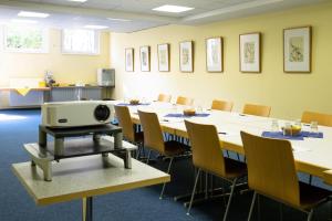 a conference room with tables and chairs and a tv on a table at Familienhotel Citylight in Berlin