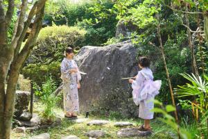 别府温泉付きの一軒家を借りよう的两个和服的女孩站在岩石旁边