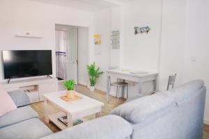 een woonkamer met een bank, een tv en een tafel bij APARTAMENTO LOS LANCES PLAYA in Tarifa