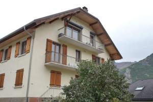 a white building with balconies and a tree at Montricher Karellis, à 5 min de Saint Jean de Maurienne in Montricher-Albanne