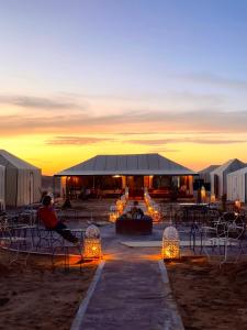 a group of tents with lights in the sunset at Merzouga Glamping With AC in Merzouga