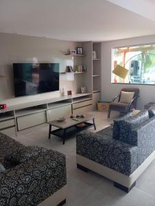 un soggiorno con un divano e una TV di Excelente casa com Piscina a Camaçari