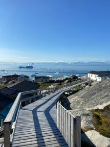 a wooden boardwalk leading down to the ocean at Ilulissat Stay - Seawatch Retreat in Ilulissat +39 photos