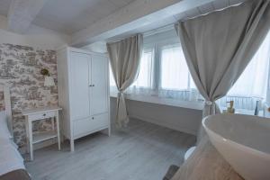 a white bathroom with a tub and a window at Sant'Andreas house 04 in Chioggia